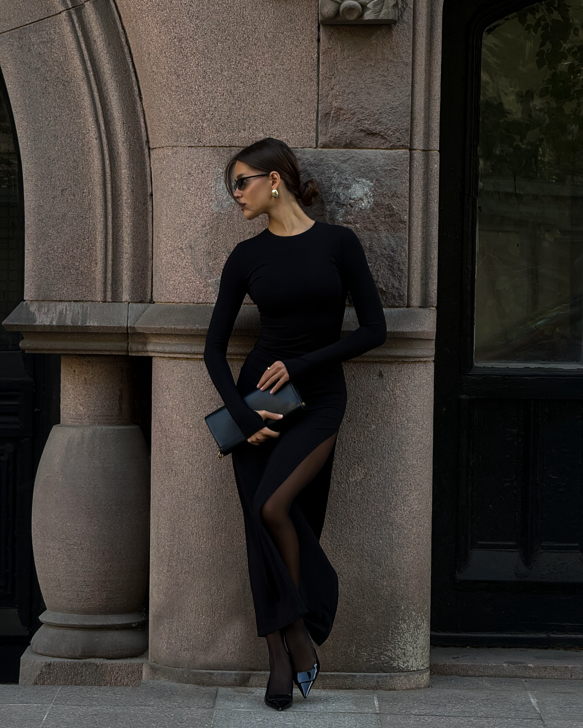 Девушка в черном платье макси с разрезом на ноге