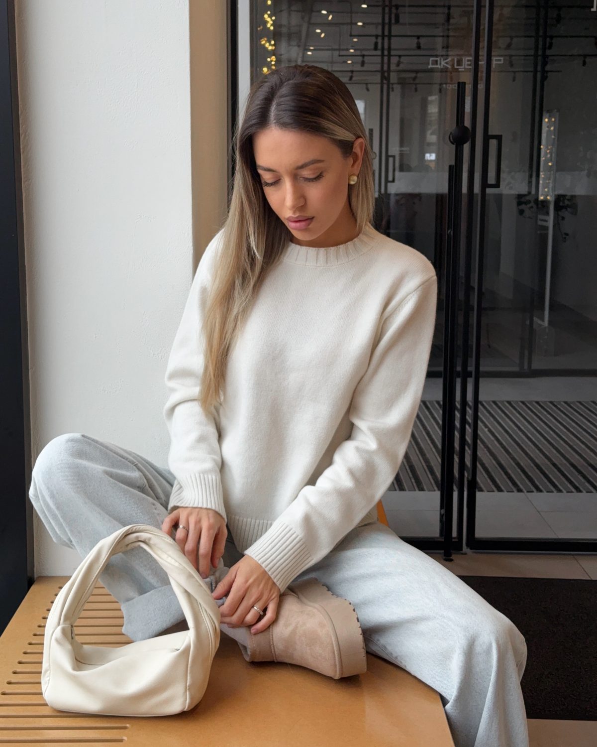 Девушка свитере молочного цвета и джинсах