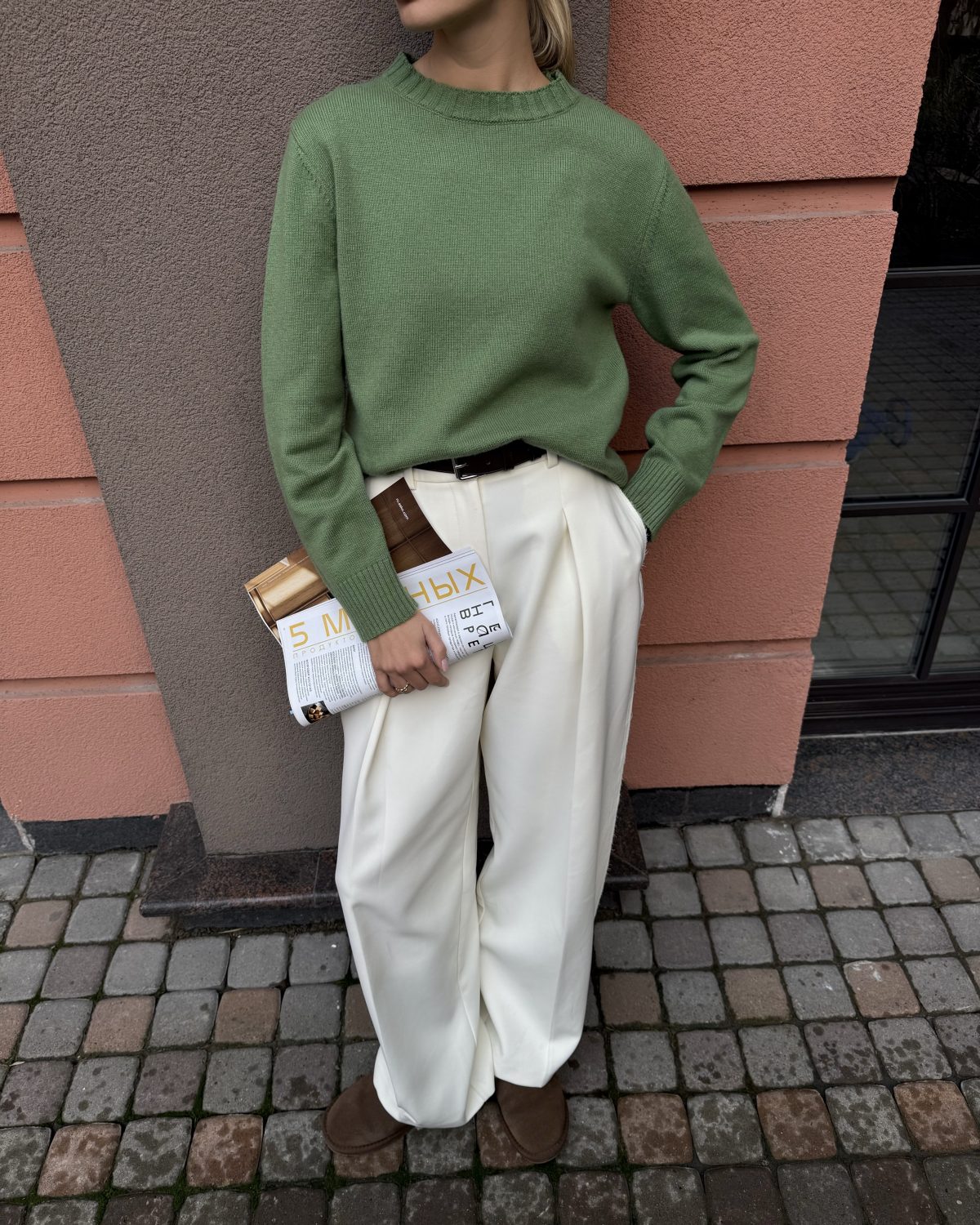 Девушка в зеленом свитере и брюках молочного цвета